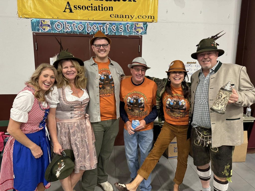 People stand dressed in Oktoberfest costume smiling