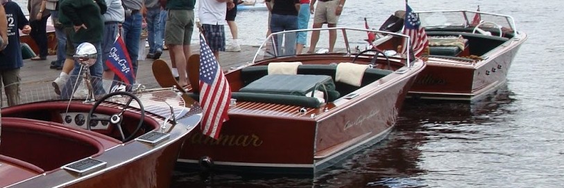 boats in a line at a boat show with people walking on a dock