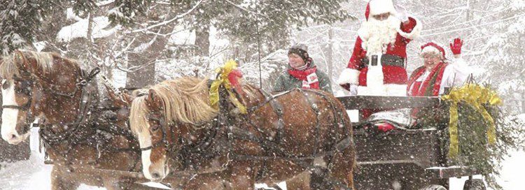 A horse drawn carriage pulling Santa and mrs clause on a snowy winter day