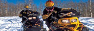 Two snowmobilers on a trail facing the camera