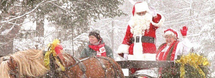 A horse drawn carriage pulling Santa and mrs clause on a snowy winter day
