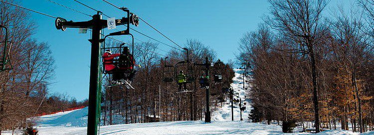 A ski lift with riders going up the mountain in winter